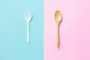 Flat lay wooden spoon white plastic spoon on pink and blue background.
