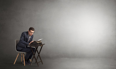 Man working hard on a typewriter in an empty space