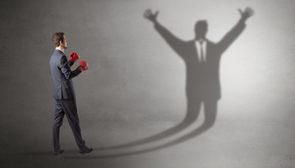 Businessman with boxing gloves fighting with disarmed businessman shadow