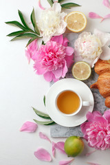 Obraz na płótnie Canvas Morning cup of tea and fresh beautiful pink and white peony flowers on white background. Top view. Flat layout, concept of female holiday morning, stylish blogger