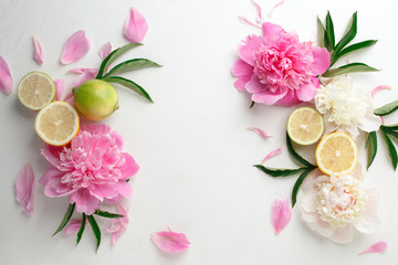 Frame made of citrus lemon, lime and peonies buds on white background. Food petal beauty concept....