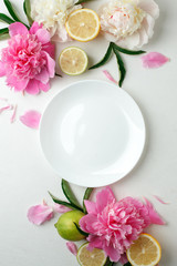 Top view of white empty plate over spring flowers. Flat lay, spring summer season holiday, femenine...