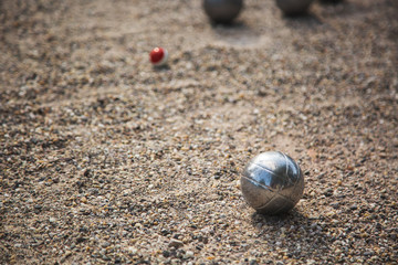 Silver Petanque or Bocce balls on gravel ground with a blur background