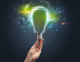 Hand holding light bulb on dark background. New business idea concept