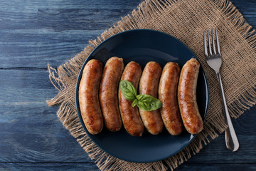 Delicious grilled sausages on a plate with red sauce and spices on a blue wooden background. B-B-Q. top view