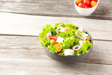 Healthy salad in bowl on wooden background