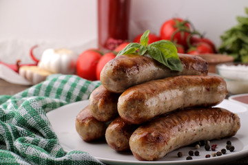 Delicious grilled sausages on a plate with red sauce and spices on a brown wooden background. B-B-Q.