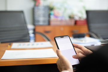 businessman hands searching for data on moblie phone with analyzing charts at his workplace.oncept