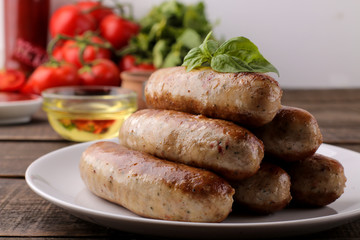 Delicious grilled sausages on a plate with red sauce and spices on a brown wooden background. B-B-Q.