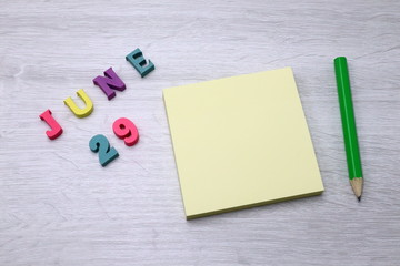 June 29 - Daily colorful Calendar with Block Notes and Pencil on wood table background, empty space for your text or design
