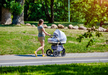 Mother wheeling a pram in the Park 
