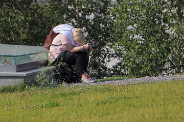 Big tired woman photographer with a camera sitting in the Park on vacation