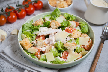 Caesar salad with chicken, Parmesan and wheat croutons on a vintage grey background. Light diet dinner.