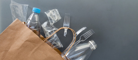 Used plastic bottles, glasses, cutlery and bags for recycling, the concept of recycling waste, ecology, land pollution on a gray background