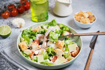Caesar salad with chicken, Parmesan and wheat croutons on a vintage grey background. Light diet dinner.