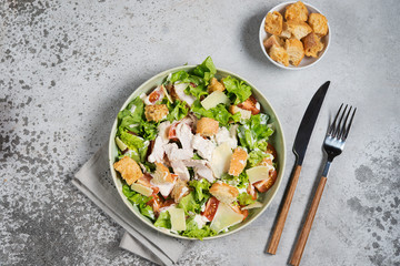 Caesar salad with chicken, Parmesan and wheat croutons on a vintage grey background. Light diet dinner.