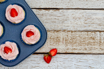decorated cupcakes on a pan white wooden table with strawberries