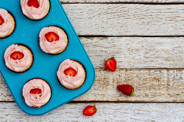decorated cupcakes on a white wooden table with strawberries