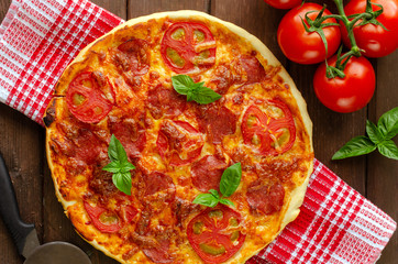 Homemade spicy pizza with sausage and tomato.