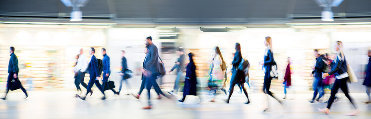 Beautiful motion blur of walking people in train station. Early morning rush hours, busy modern life concept. Ideal for websites and magazines layouts
