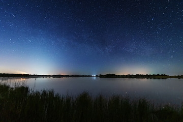 Magic starry night with the galaxy Milky way near the river with a large tree