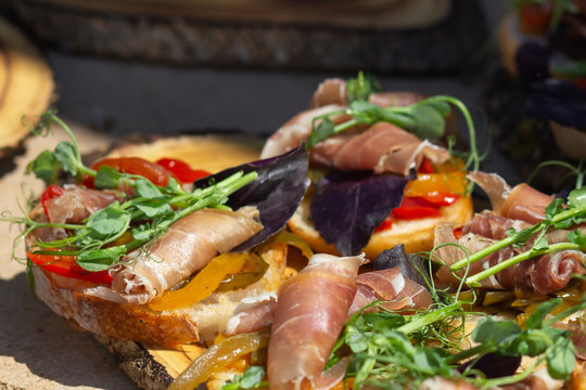 Close up bruschetta with proschuto, tomato, parmesan cheese and arugula