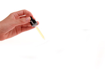 Cosmetic pipette in the hand on white background. Essential oil falling from glass dropper