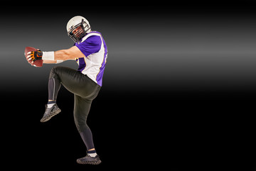American football player in motion with the ball on a black background with a light line, copy space. The concept of the game is American football, movement.