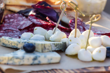 Cheese plates served with grapes, jam, figs, crackers and nuts on a wooden background,