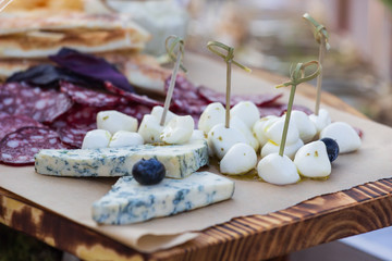 Cheese plates served with grapes, jam, figs, crackers and nuts on a wooden background,