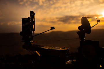 Silhouettes of satellite dishes or radio antennas against sunset sky. Space observatory.