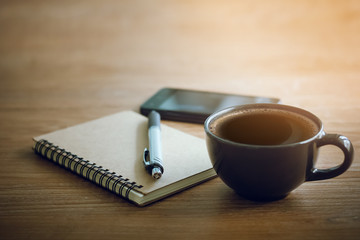Closeup of notebook and pen with soft focus on black coffee and smartphone. Concept rest after work