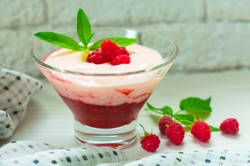  Yogurt with berry mousse decorated with raspberries and mint on a white table.