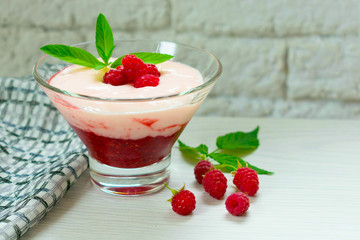  Yogurt with berry mousse decorated with raspberries and mint on a white table.