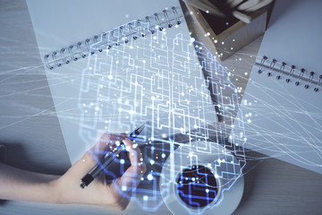 Multi exposure of woman's writing hand on background with brain hologram. Concept of brainstorming.