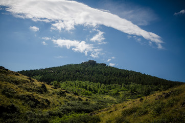 Beautiful mountain peak in clouds with rocks and pine forest