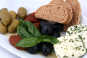 Assorted olives on a white plate. Sun-dried tomatoes, feta cheese and bread. Classic italian appetizer. Close-up on a white background.