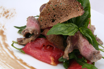 warm salad with meat, vegetables and greens. close up on a white background