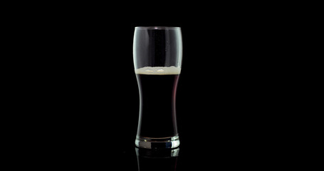 Craft black Beer in a glass isolated on black color background.