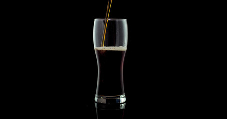Cold Craft black Beer in a glass isolated on black color background.