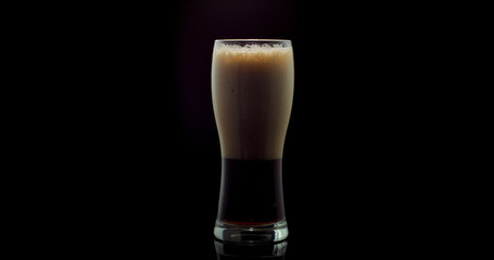 Cold Craft dark Beer in a glass isolated on black color background.