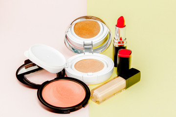 Make up products spilling on to a bright yellow and pink background with copy space