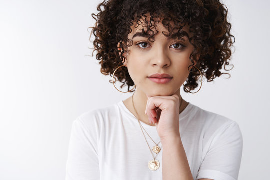 Thoughtful powerful good-looking curly-haired stylish 25s woman hold hand face-line gaze camera confident alluring listen intersting story thinking, taking important decision, white background