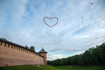 Fototapeta na wymiar Veliky Novgorod. Kremlin. Red balloons in the sky in the form of a heart over the Kremlin. Summer view