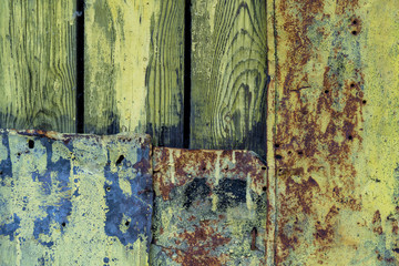 old faded wooden planks and metal patch for them. Metal patch on the wooden door. Green peeling wooden background