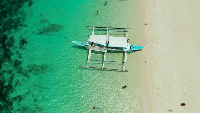 Tropical white sand beach, near the blue lagoon and corall reef from above, Boracay, Philippines. Sandy beach with tourists. Summer and travel vacation concept.
