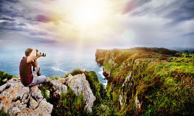 Concepto de aventura y viajes de naturaleza. Fotógrafo en acción con su equipo durante la puesta de sol en un paisaje de playa en Cantabria, España.