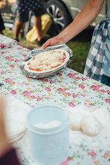 Male chef preparing dough for pizza in outdoor market. Street food.