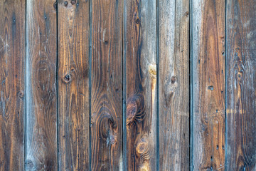 old wooden fence. Faded wooden planks with corrosion. Peeled wooden door of several boards. Old natural wooden board without paint.