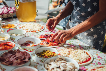 Male chef preparing dough for pizza in outdoor market. Street food.